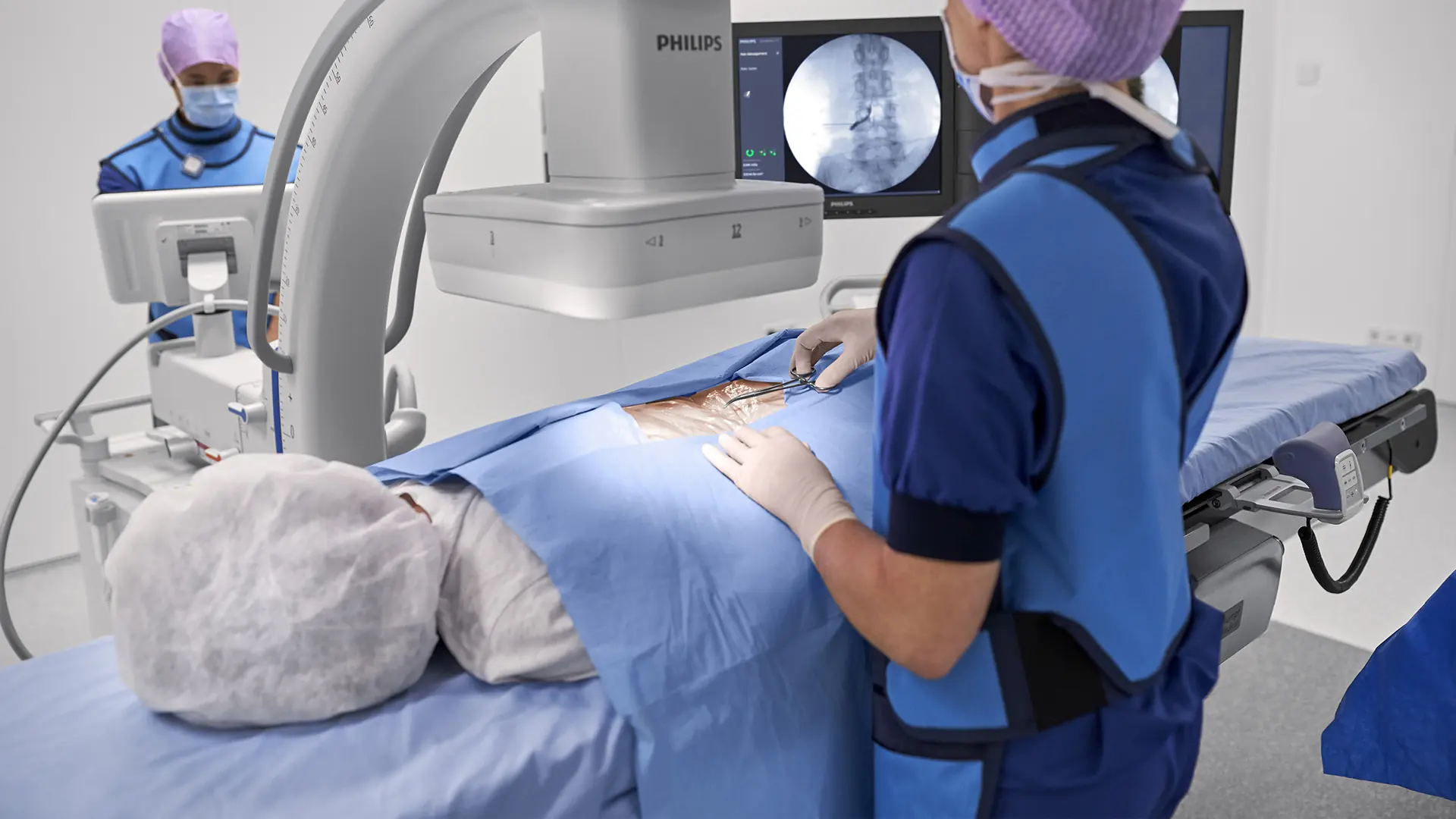 Clinicians using a C-arm imaging system with a patient on a procedure table