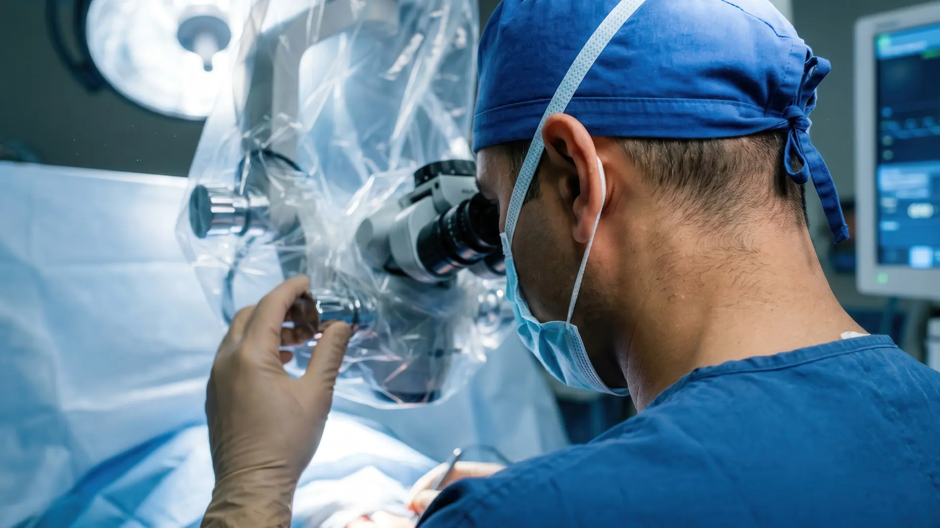Surgeon looking through a covered surgical microscope during a procedure